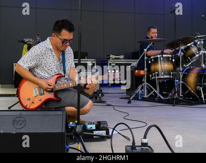 Gitarrist Airman 1st Class Christopher Arellano und Schlagzeuger Tech. Sgt. Andy Wendzikowski stimmt ihre Instrumente vor einer Performance von Flight One am 7. August 2021 im Levitt Pavilion in Dayton, Ohio. Die Band, stationiert auf der Wright-Patterson Air Force Base, spielt im gesamten Bundesstaat als Teil ihrer Community-Outreach-Mission. Stockfoto