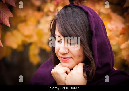 Outdoor-Porträt der schönen jungen Frau und bunten Herbstblatt, Porträt der schönen jungen Frau mit Piercing Stockfoto