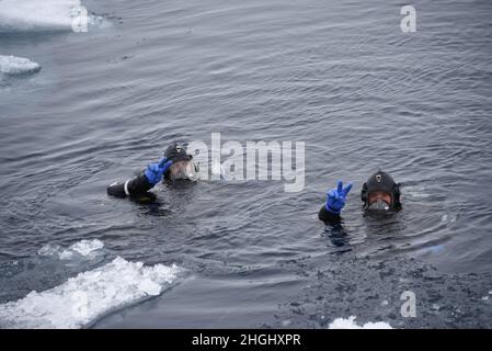 Die Mitglieder der Küstenwache, Cutter Healys temporäres regionales Tauchlocker-Team, (links) Petty Officer 2nd Klasse Connor Dahl und (rechts) Petty Officer 1st Klasse Daniel Darder, führen einen Einarbeitungstauchgang in der Tschuktschen See durch, 9. August 2021. Während des Einsatzes der Nordwestpassage der Healy arbeiten der Cutter und die Crew innerhalb des ersten und mehrjährigen Eises in der gesamten Arktis und dokumentieren, wie sich die unterschiedlichen arktischen Sommerbedingungen auf die Einsätze der Küstenwache auswirken. Stockfoto