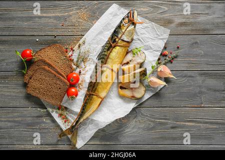 Geräucherter Makrelenfisch und Brot auf grauem Holzhintergrund Stockfoto