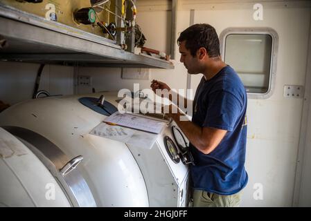 Der Navy Diver Brandon Barreto der 2. Klasse, der der Mobile Diving Salvage Unit (MDSU) 2 zugewiesen wurde, führt während der großen Übung (LSE 2021) an Bord des ultraleichten Interventionsschiffs MV Connor Bordelon Betriebsabläufe auf einem transportablen Rekompressionskammersystem (TRCS) durch. LSE 2021 demonstriert die Fähigkeit der Marine, weltweit präzise, tödliche und überwältigende Gewalt über drei Seestreitkommandos, fünf nummerierte Flotten und 17 Zeitzonen hinweg einzusetzen. LSE 2021 vereint Live- und synthetische Trainingsfunktionen, um eine intensive, robuste Trainingsumgebung zu schaffen. Es verbindet High-Fidelity-Training und Stockfoto