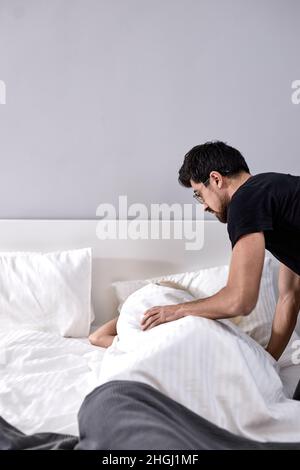 wake up Liebling. Guten Morgen. Mann aufwachen Frau, schlafen im Schlafzimmer zu Hause. Am Wochenende, vorsichtig freundlich schönen bärtigen Mann berühren Frau. Drinnen Stockfoto