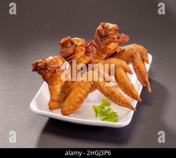 Gegrillte, würzige Chicken Wings in weißem Tablett auf dunkelgrauem Hintergrund, Draufsicht Stockfoto