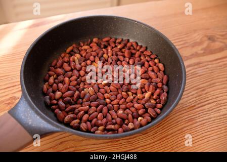 Gebratene Erdnüsse in einer Pfanne auf einem Holztisch. Stockfoto