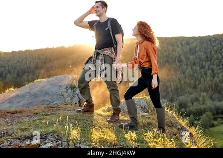 Junge Paar Wanderer halten die Hände zusammen und genießen die wunderschöne Landschaft der Natur in den Bergen. Warmer sonniger Tag auf dem Land. Aktiver Lebensstil, Reisen Stockfoto