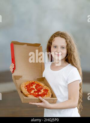 Happy Little girl Holding box mit Pepperoni Pizza. Stockfoto