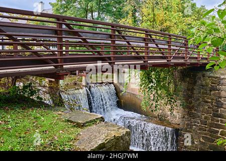 Ein Wasserüberlauf vom Delaware-Kanal in den Delaware River mit einer Metallbrücke in Lambertville, New Jersey, New Hope Pennsylvania. Stockfoto