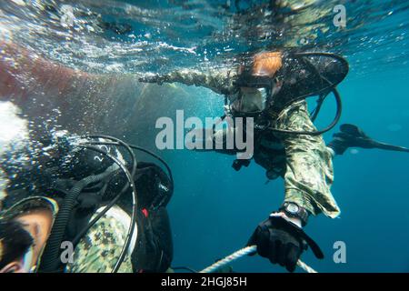 Navy Diver Brandon Barreto der 2. Klasse und Navy Diver Aiden Lockard der 3. Klasse, die beide der Mobile Diving Salvage Unit (MDSU) 2 zugeordnet sind, führen während großer Übung (LSE 2021) Unterwasser-Kampfschadenreparaturen (BDR) auf dem Zerstörer USS Gonzales der Arleigh Burke-Klasse (DDG-66) durch. LSE 2021 demonstriert die Fähigkeit der Marine, weltweit präzise, tödliche und überwältigende Gewalt über drei Seestreitkommandos, fünf nummerierte Flotten und 17 Zeitzonen hinweg einzusetzen. LSE 2021 vereint Live- und synthetische Trainingsfunktionen, um eine intensive, robuste Trainingsumgebung zu schaffen. Es wird High-Fidelit angeschlossen Stockfoto