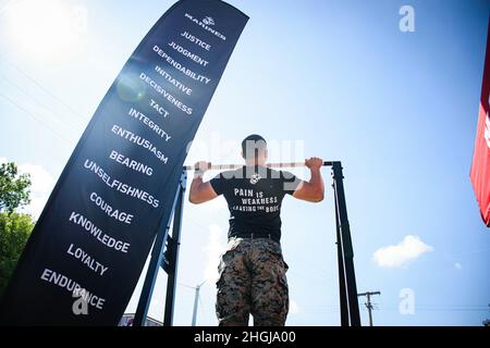 U.S. Marine Staff Sgt. Jorden MacIntyre, ein Rekrutierer bei der Recruiting Station Cleveland, zeigt auf der Cuyahoga County Fair in Middleburg Heights, Ohio, am 14. August 2021 die richtige Form für einen Pull-up. Ziel der Veranstaltung war es, dass sich Rekrutierer mit der lokalen Gemeinschaft auseinandersetzen und Zivilisten zur Teilnahme an einer Pull-up-Herausforderung einladen, um die Preise des Marine Corps zu erhalten. Stockfoto