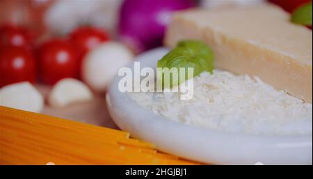 Frische Zutaten auf Holztisch in der Küche. Parmesankäse reiben. Stockfoto