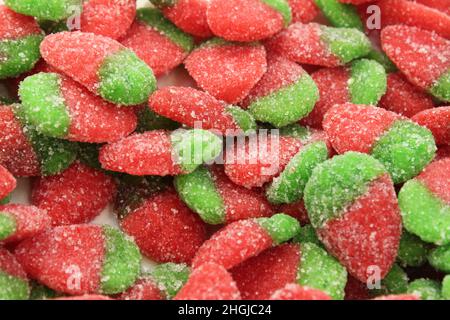 Kauen Erdbeer-förmige Marmelade rot mit grün in Zucker Nahaufnahme von Lebensmitteln Hintergrund. Stockfoto