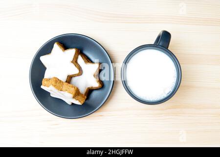 Teller mit Zimt-Stern-Keksen und einer Tasse Milch, die an einem Heiligabend für den Weihnachtsmann ausgelassen wurden. Stockfoto