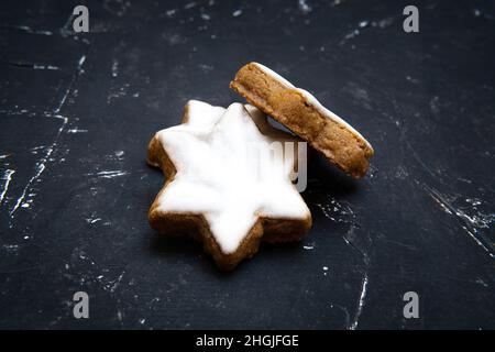 Authentische deutsche Zimt-Star-Cookies auf einem texturierten schwarzen Hintergrund. Stockfoto