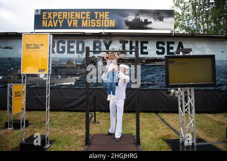 CENTRALIA, Washington (Aug 20, 2021)-Navy Counselor First Class Jacob Karlik, der Navy Recruiting Station Olympia zugewiesen wurde, unterstützt den vierjährigen Liam Inigauz spielerisch bei der Pull-up-Herausforderung der Navy im Rahmen des „Nimitz“ Virtual Reality-Erlebnisses der Navy auf der Southwest Washington Fair. Navy Talent Acquisition Group der Zuständigkeitsbereich von Pacific Northwest umfasst mehr als 34 Navy Recruiting Stations und Navy Officer Recruiting Stations in ganz Washington, Idaho, Montana und Alaska. Stockfoto