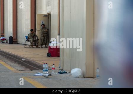 Zwei Mitglieder der 379th Expeditionary Security Forces Squadron stehen am Eingang eines Hangars, wo qualifizierte Evakuierte sich auf den Transit zu ihrem nächsten Ziel vorbereiten am 20. August 2021 auf der Al Udeid Air Base, Katar. Das Verteidigungsministerium hat sich verpflichtet, das US-Außenministerium beim Ausscheiden von US-amerikanischem und alliiertem Zivilpersonal aus Afghanistan zu unterstützen und die afghanischen Verbündeten in Sicherheit zu bringen. Stockfoto