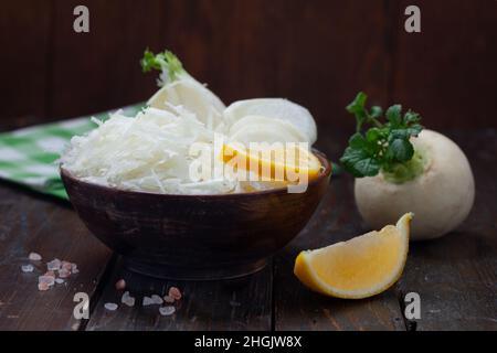 Roher weißer Rüben-Salat in Holzschüssel. Leckerer frischer Salat aus weißem japanischer Rettich. Gesundes, vegetarisches Essen. Stockfoto