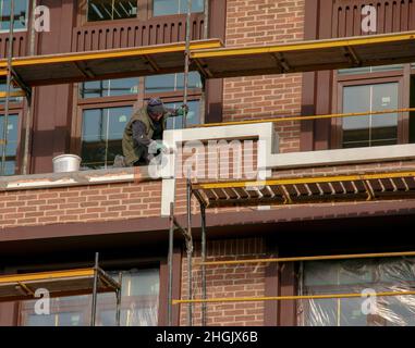 Dnipropetrovsk, Ukraine - 11.22.2021: Bauherren führen die Fertigstellung der Fassade auf dem Gerüst durch Stockfoto