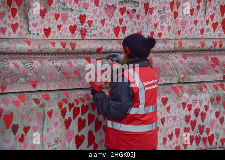 London, Großbritannien. 21st Januar 2022. Ein Freiwilliger malt Herzen an der National Covid-19 Memorial Wall.Freiwillige malen weiterhin neue Herzen und malen einige, die im Laufe der Zeit verblasst sind. Über 150.000 rote Herzen wurden bis heute an die Wand vor dem St. Thomas' Hospital gegenüber dem Parlamentsgebäude gemalt, eines für jedes Leben, das COVID-19 verloren hat. (Foto: Vuk Valcic/SOPA Images/Sipa USA) Quelle: SIPA USA/Alamy Live News Stockfoto