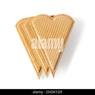 Drei herzförmige Wafer zum Garnieren isoliert auf weißem Hintergrund. Dünne flache Waffelplätzchen zur Eisdekoration. Makro. Gebackenes Weizengebäck Stockfoto