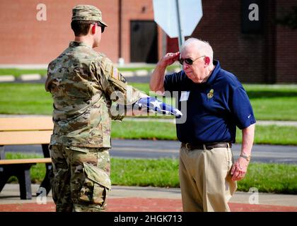 Der pensionierte Major General James Williams (rechts) grüßt als Staff Sgt. Aaron Garretson, von Company A, Bataillon 1st, Infanterie-Regiment 148th, Kampfteam der Infanterie-Brigade 37th, überreicht die gefaltete amerikanische Flagge während einer Retreat-Zeremonie am 28. August 2021 in Camp Perry, Ohio. Die Zeremonie fand im Rahmen der gemeinsamen Versammlung der 148th Infantry Veterans Association und der 37th Division Veterans Association statt. Stockfoto