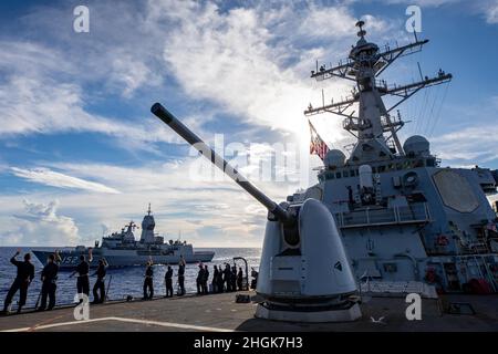 PHILIPPINISCHES MEER (Aug 29, 2021) Matrosen an Bord des Arleigh Burke-Klasse-Lenkflugkörper-Zerstörers USS Barry (DDG 52) winken während MALABAR 2021 zur Königlich Australischen Navy Anzac-Klasse Fregatte HMAS Warramunga (FFH 152). Barry wird derzeit zur Unterstützung von Commander, Task Force (CTF) 71/Destroyer Squadron (DESRON) 15, der größten vorwärtseingesetzten DESRON der Marine und der wichtigsten Surface Force der US-Flotte der 7. Flotte eingesetzt. Stockfoto