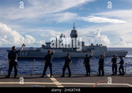 PHILIPPINISCHES MEER (Aug 29, 2021) Matrosen an Bord des Arleigh Burke-Klasse-Lenkflugkörper-Zerstörers USS Barry (DDG 52) winken während MALABAR 2021 zur Königlich Australischen Navy Anzac-Klasse Fregatte HMAS Warramunga (FFH 152). Barry wird derzeit zur Unterstützung von Commander, Task Force (CTF) 71/Destroyer Squadron (DESRON) 15, der größten vorwärtseingesetzten DESRON der Marine und der wichtigsten Surface Force der US-Flotte der 7. Flotte eingesetzt. Stockfoto