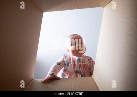 Glückliches Baby in Paketkarton und lächelnd. Stockfoto