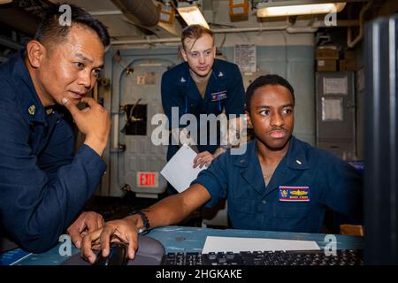 PHILIPPINISCHES MEER (Aug 31, 2021) LT. j.g. Mario Evans, (rechts), aus Powder Springs, Georgia, erhält eine Ausbildung als Ingenieurin vom Chief Gas Turbine Systems Technician (Mechanical) Dexter Jay Anis, (links), aus Seattle, an Bord des Arleigh Burke-Klasse Lenkraketen-Zerstörers USS Barry (DDG 52). Barry wird eingesetzt, um Commander, Task Force (CTF) 71/Destroyer Squadron (DESRON) 15, die größte vorwärtseingesetzte DESRON der Marine und die wichtigste Surface Force der US-Flotte von 7th, zu unterstützen. Stockfoto