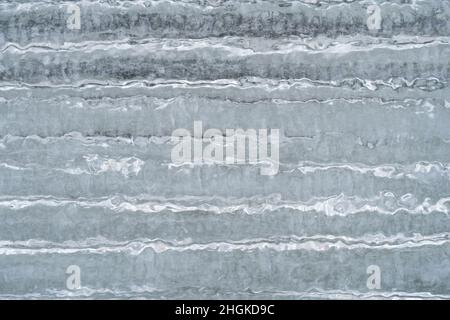 Eiszapfen und Eisstruktur in Nahaufnahme. Klares, gefrorenes Wasser, das durch den Schnee am Tag geschmolzen und in der Nacht gefroren wurde Stockfoto