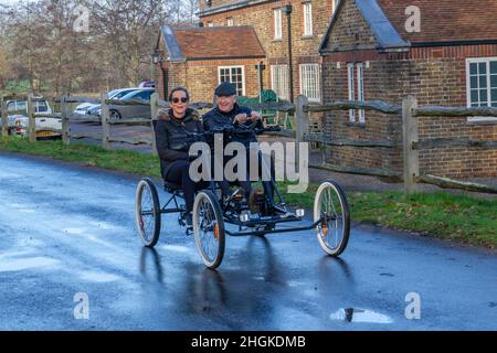 Mann und Frau auf einem vierrädrigen Zweisitzer-Fahrrad, das durch das Dorf im Windsor Great Park, Windsor, Bergshire, Großbritannien, fährt. Stockfoto