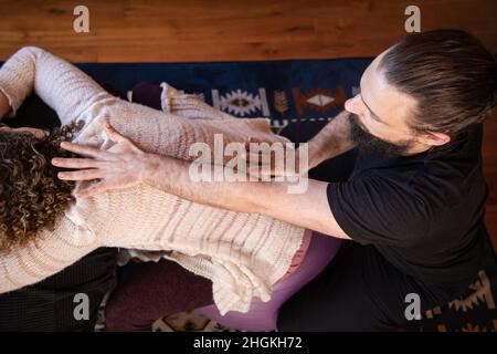 Über dem Kopf angeschossen, als ein Shiatsu-Praktizierender die Qi-Meridianpunkte über dem Rücken einer Dame findet. Traditionelle japanische Körperarbeit mit Qigong Lebensenergie. Stockfoto