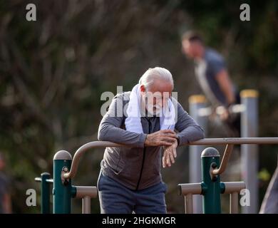 Seniorchef, der eine Smart Watch verwendet und die Ergebnisse nach dem Fitnesstraining im öffentlichen Fitnessstudio im Freien verfolgt Stockfoto