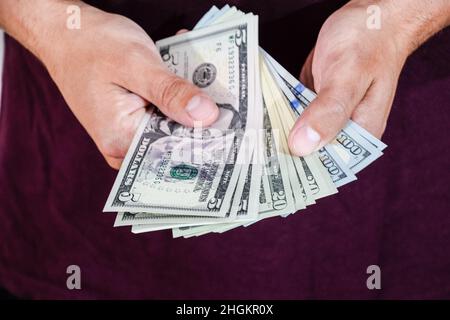 Ein Mann hält einen Geldwad in den Händen. US-Dollar Stockfoto