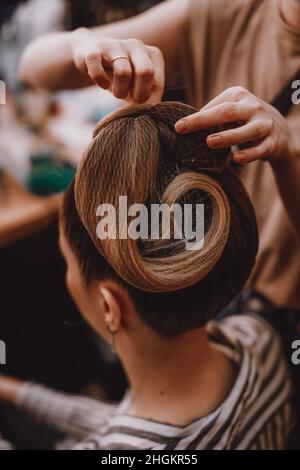 Weibliche Hände machen Vintage Frisur auf blondem Haar Stockfoto