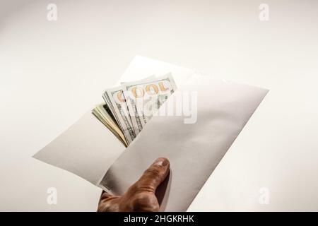 Dollar im Wind auf weißem Hintergrund, viel Geld in einem Umschlag. Stockfoto