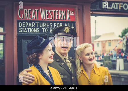 1940s Veranstaltung in Severn Valley Railway, Kidderminster Station, Großbritannien. Mann in Uniform steht im Foyer mit zwei Frauen in Kriegskostüm. Stockfoto