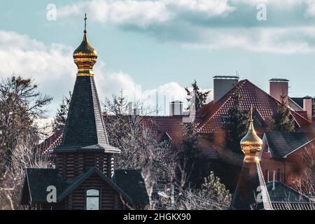 Goldene Kuppel mit Kreuz auf Holzkirche oben Blick auf malerischen blauen Himmel. Architektonische Details in der Ukraine, Charkiw-Stadt Stockfoto