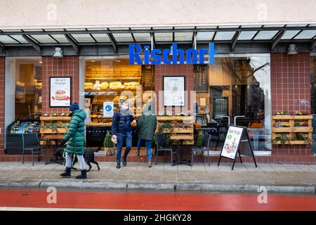 München, Deutschland. 21st Januar 2022. Einkäufer betreten und verlassen eine Rischart Bäckerei. Während die Fälle von Covid-19 weiter ansteigen, gibt es sowohl von Politikern als auch von der Öffentlichkeit Widerstand, weitere Beschränkungen zu setzen. Die siebentägige Inzidenz in der Stadt München hat 1.122 erreicht. Doch am Nachmittag des 21. Januar 2022 konnten viele Menschen beim Einkaufen gesehen werden. (Foto: Alexander Pohl/Sipa USA) Quelle: SIPA USA/Alamy Live News Stockfoto