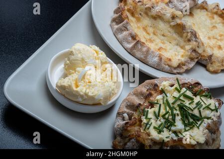 Helsinki / Finnland - 21. JANUAR 2022: Traditionelle finnische Speisen - frische karelische Torten mit Eierbutter und Schnittlauch auf schwarzem Hintergrund. Stockfoto