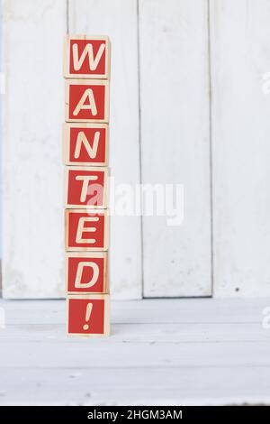 Holzwürfel, mit dem Wort Wanted, auf weißem Hintergrund Stockfoto