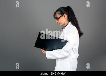 40-45-jährige Ärztin, die im Ordner schreibt, Profilansicht Stockfoto