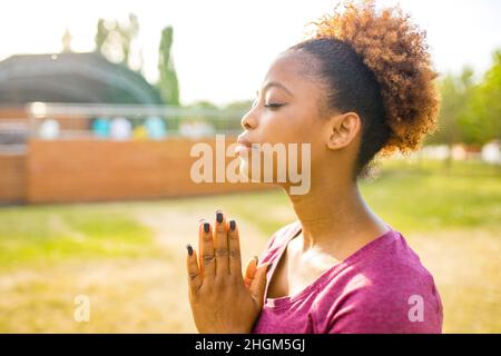 Glückliche junge afroamerikanische Frau Trainer mit kurzen lockigen Haaren bereit für Yoga-Zeit im Freien Stockfoto