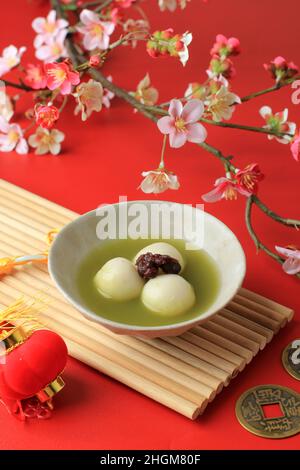 Matcha Big Tangyuan (Tang Yuan) mit süßer Matcha-Suppe in Holzschale auf schwarzem Holztischhintergrund für die Wintersonnenwende beim Festessen Stockfoto