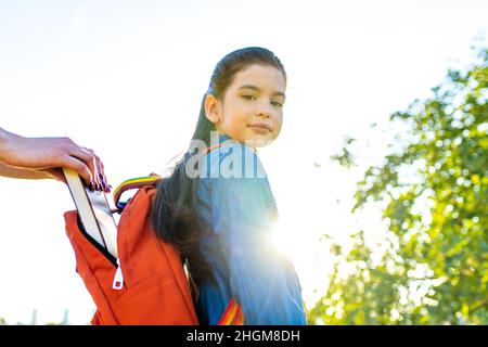 Lächelndes indisches Studentenmädchen in Schulrucksack und blauem T-Shirt im Park Stockfoto