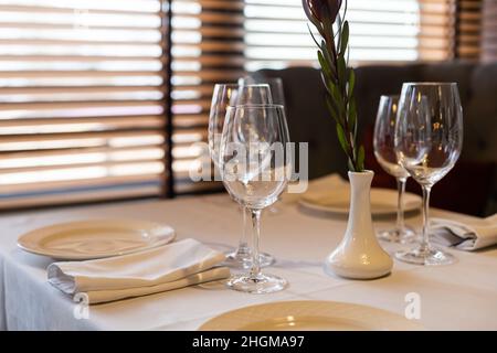 Wunderschön gedeckte Tische mit Gläsern und Geräten am Morgen im Restaurant Stockfoto