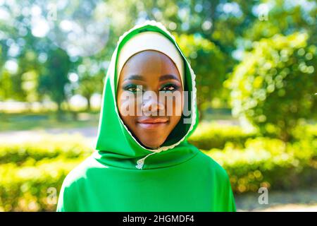 Schöne moderne Studentin in Hijab mit Make-up und Piercing Ring auf der Nase draußen Stockfoto