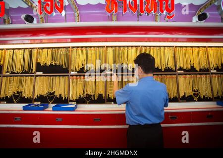 Bangkok, Thailand. 21st Januar 2022. Ein Mitarbeiter, der als Schutzmaßnahme gegen die Verbreitung von Covid-19 eine Gesichtsmaske trägt, nimmt eine der Goldketten zum Verkauf im Goldschmuckladen in Bangkoks Chinatown heraus. Goldläden in Bangkoks chinesischer Stadt bereiten sich auf das Geschäft vor dem bevorstehenden chinesischen Neujahr 2022 in Thailand vor. Kredit: SOPA Images Limited/Alamy Live Nachrichten Stockfoto