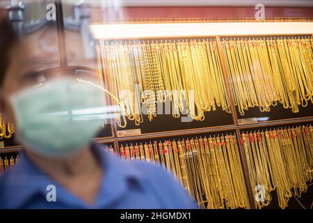 Bangkok, Thailand. 21st Januar 2022. Ein Mitarbeiter, der als Schutzmaßnahme gegen die Verbreitung von Covid-19 eine Gesichtsmaske trägt, wartet im Goldschmuckladen in Bangkoks Chinatown auf Kunden. Goldläden in Bangkoks chinesischer Stadt bereiten sich auf das Geschäft vor dem bevorstehenden chinesischen Neujahr 2022 in Thailand vor. (Foto von Adisorn Chabsungnoen/SOPA IMAG/Sipa USA) Quelle: SIPA USA/Alamy Live News Stockfoto