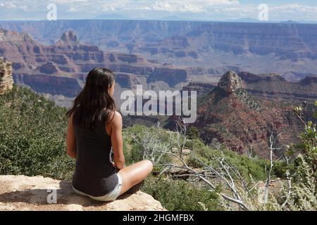 Eine sitzende junge Wanderin nimmt den Blick vom Nordrand des Grand Canyon am Widforss Point auf Stockfoto