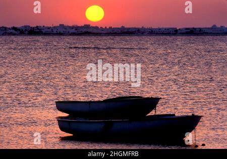 Dinghy-Boote und Sonnenuntergang an der Küste, Djerba, Tunesien Stockfoto